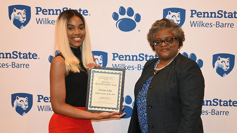 A woman at right presents an award to a woman at left.
