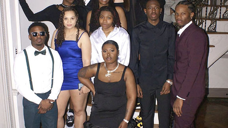 A large group of students wearing dressy clothing and sneakers in front of a staircase.