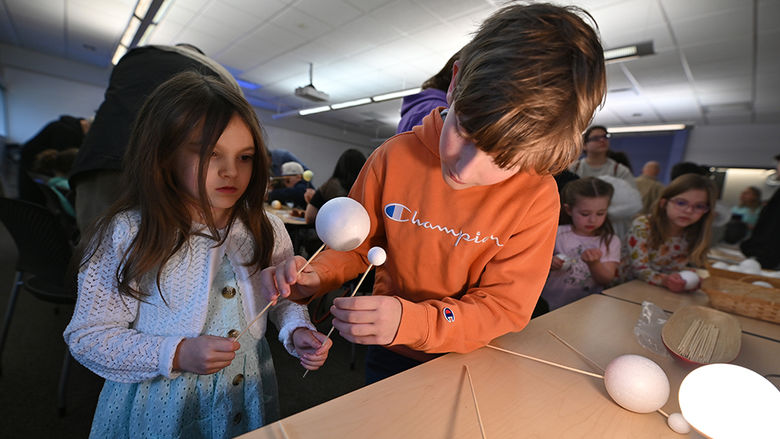 A young girl and boy working on an eclipse craft.
