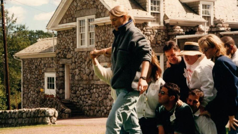 A group of people outside with a stone building behind them.