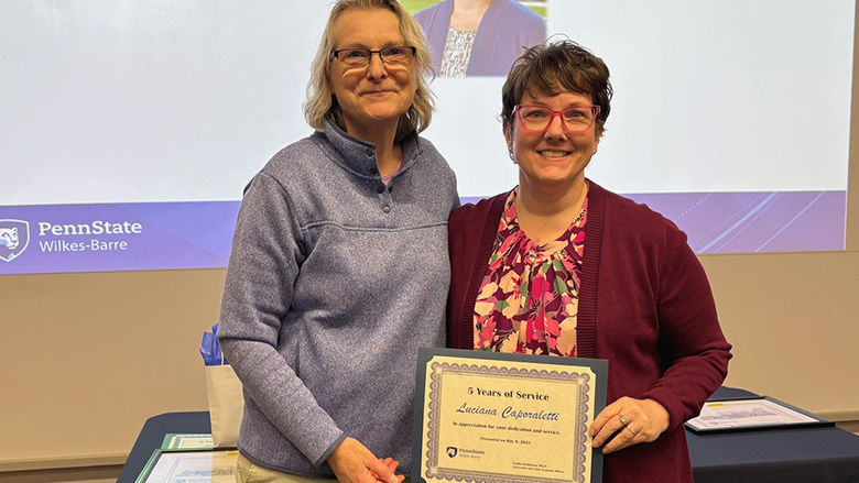 A woman at left presenting an award to a woman at right.