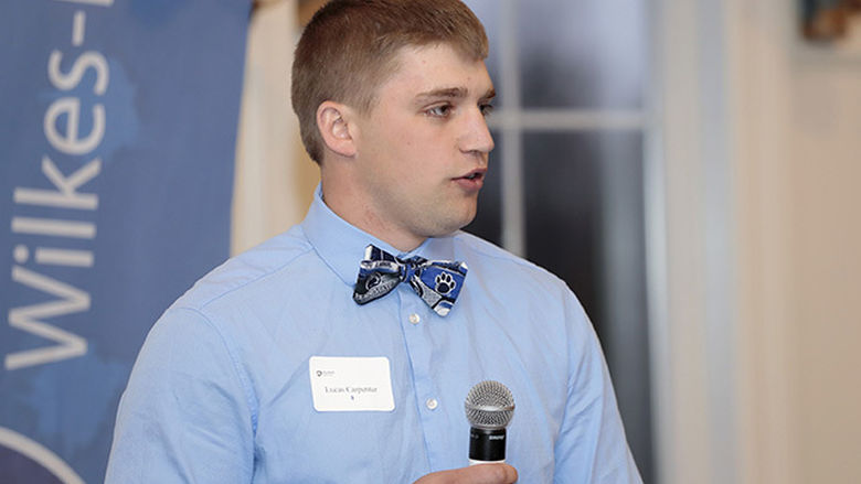 A male student speaking while holding a microphone.