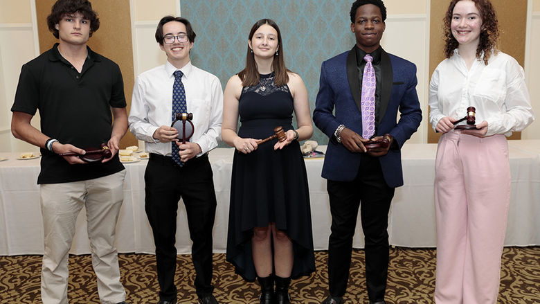 Five people standing alongside each other indoors.