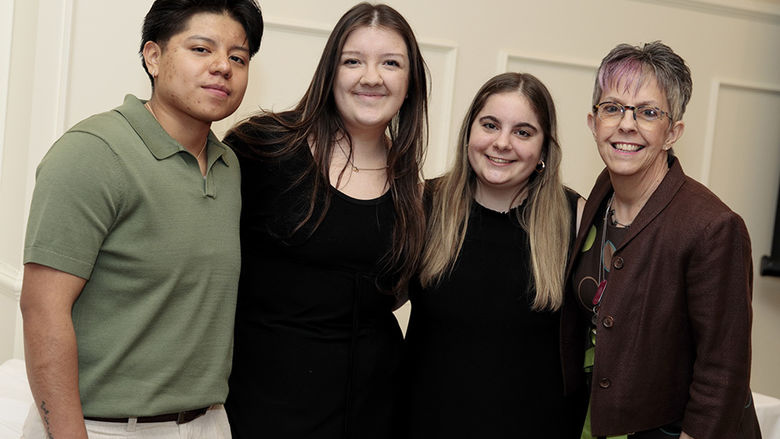 Four people standing alongside each other indoors.