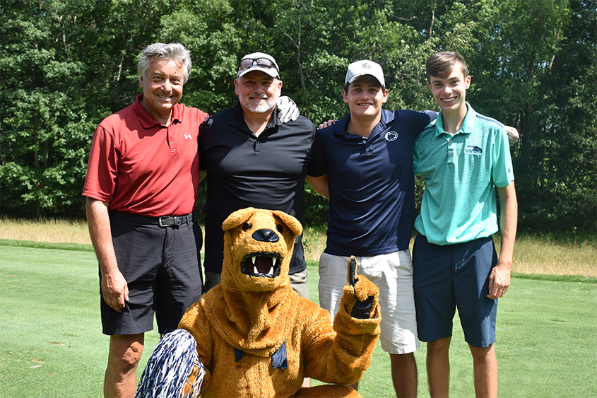 The winning team posing on the green with the Nittany Lion Mascot
