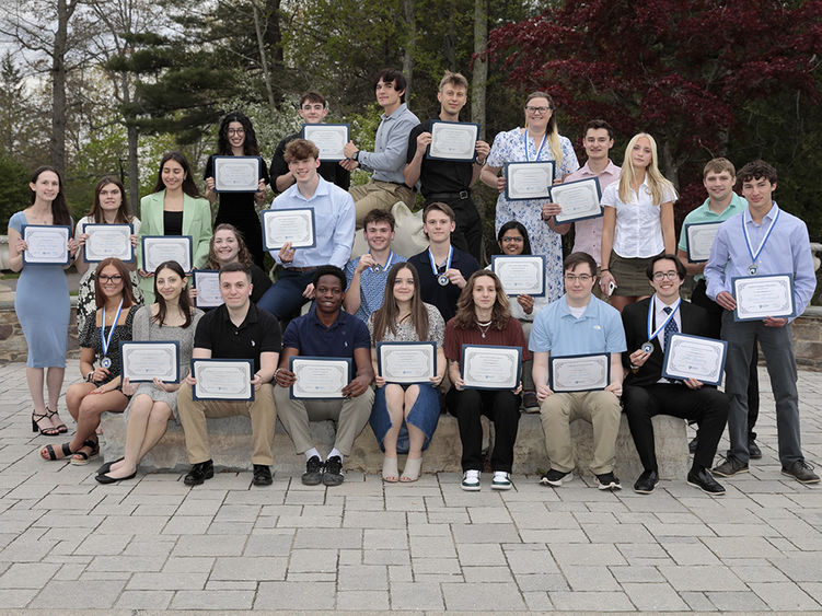 A large group of students posing outside around the Nittany Lion statue.