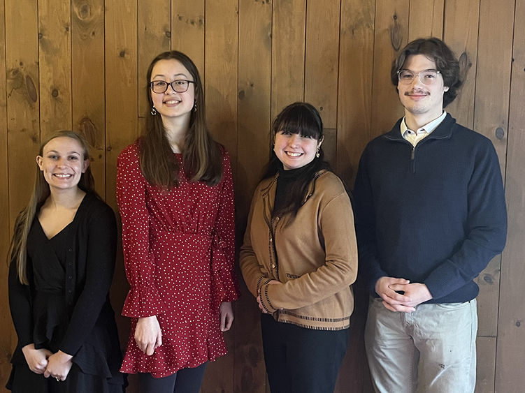 A group of four students standing against a wall