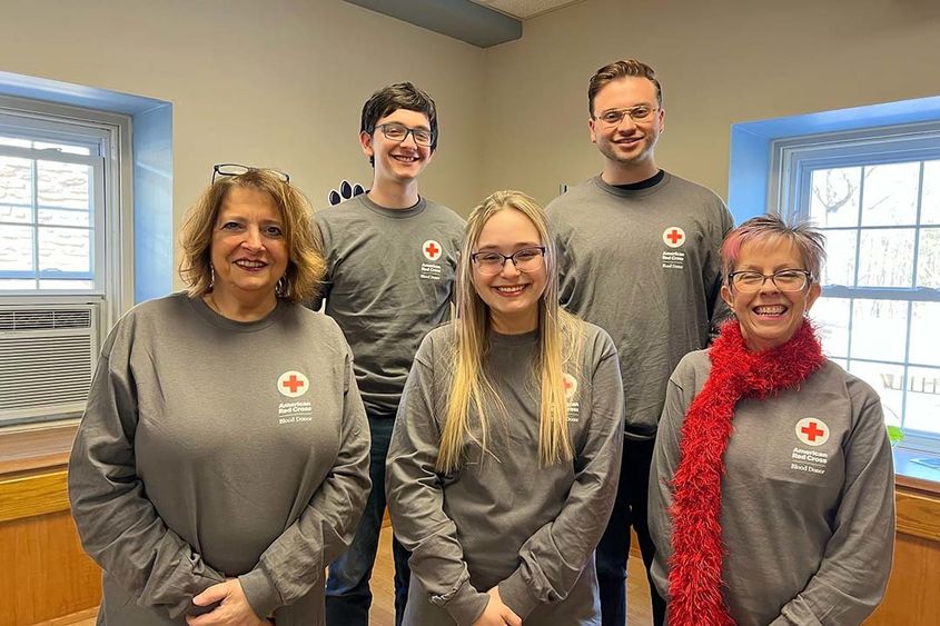 A group of people standing together wearing Red Cross T-shirts