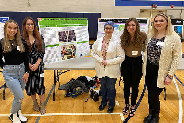 Four people stand with posters at the event.