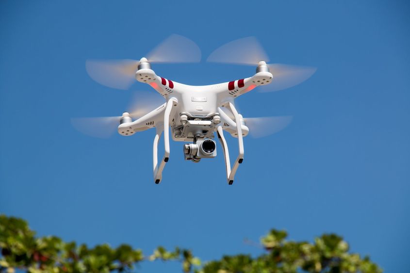 white drone flying in a blue, clear sky