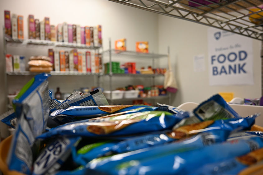 A close-up of granola bars with other food on shelves in the background