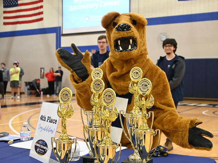 The Nittany Lion standing behind a table of trophies.