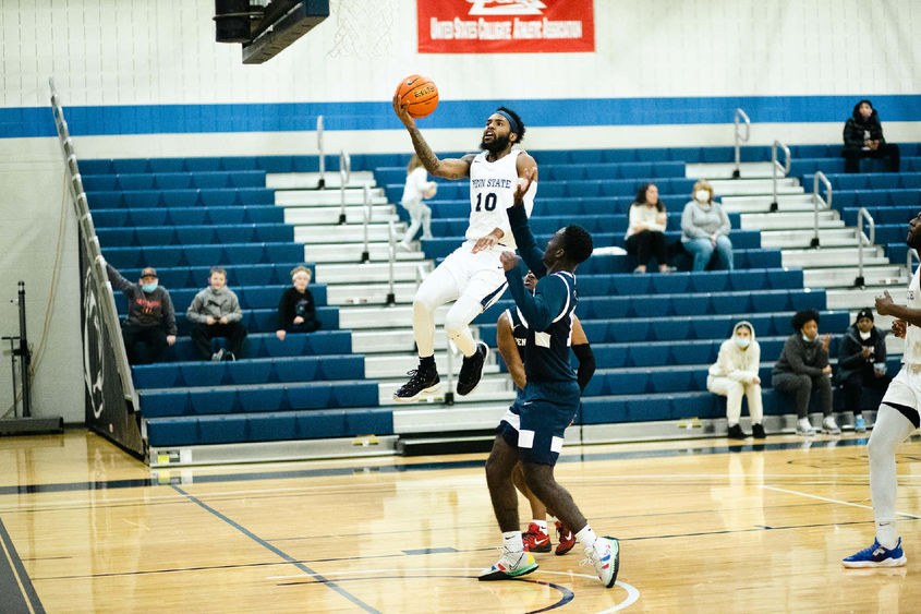 A man with basketball in hand jumping up toward the basket.