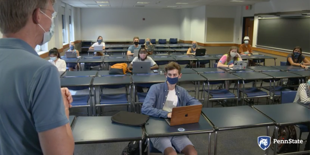 An instructor stands before a socially distanced classroom.