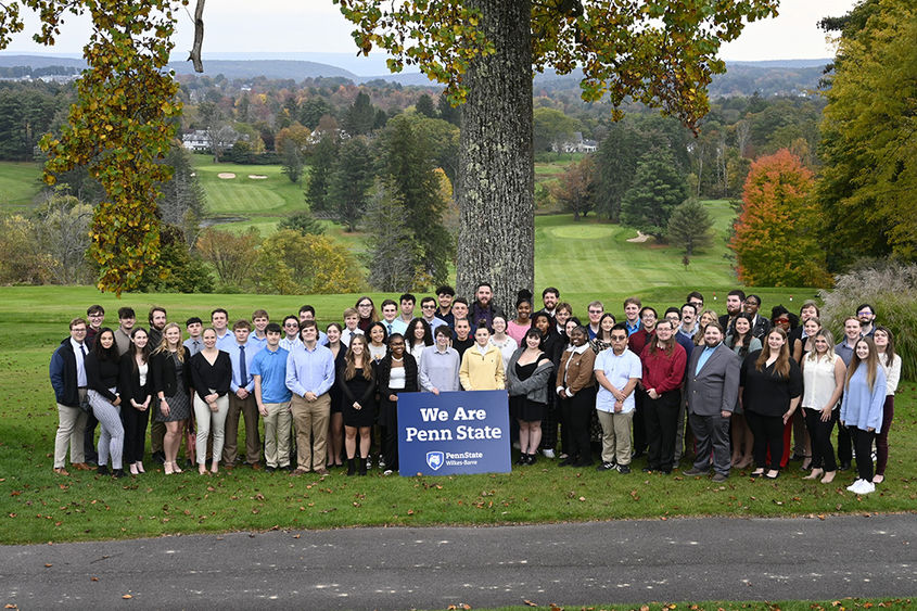 A large group of students standing outdoors with a sign that says We Are Penn State