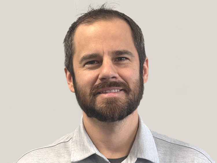 A headshot of a man against a light gray background.