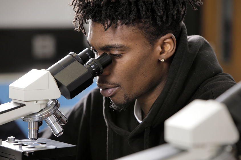 Close up of student looking through microscope