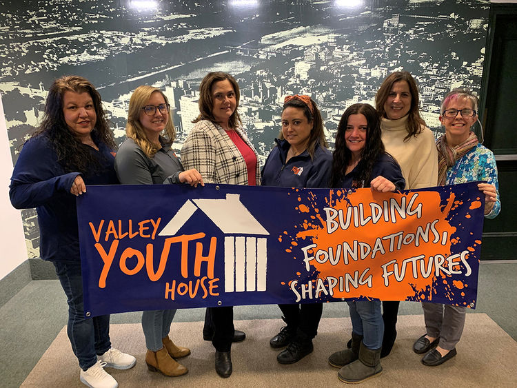 A group standing with a banner at Valley Youth House