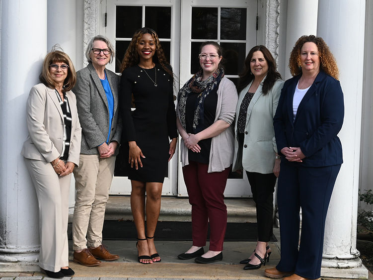 A group of six women standing in front of historic Hayfield House.