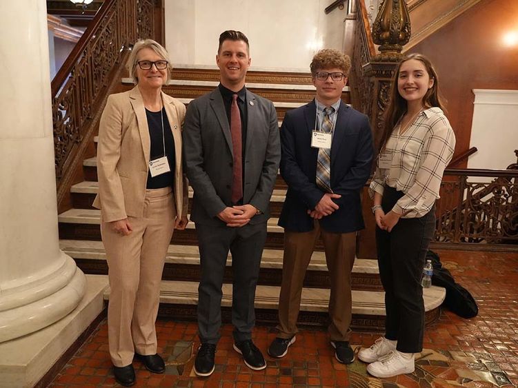 Four people standing in front of a set of stairs.