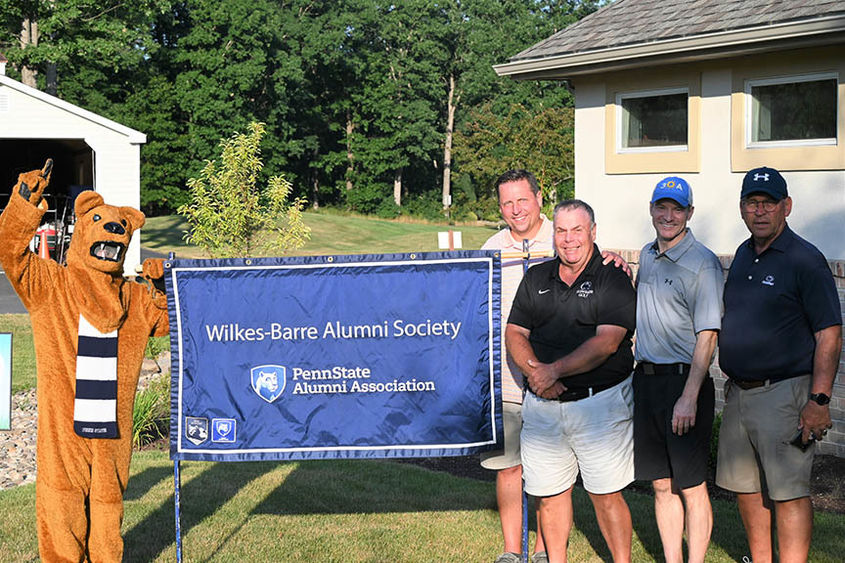 Golf tournament winners posing with the Nittany Lion